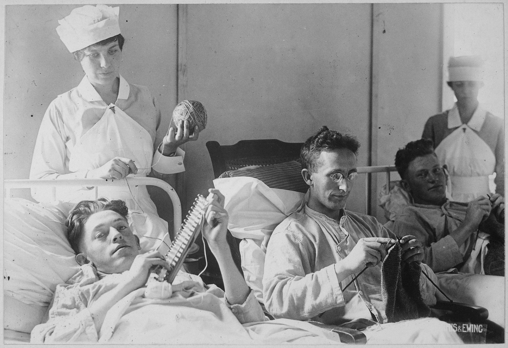 nurse overseeing bed ridden veterans who are knitting
