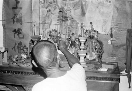 A man places incense on his home altar.